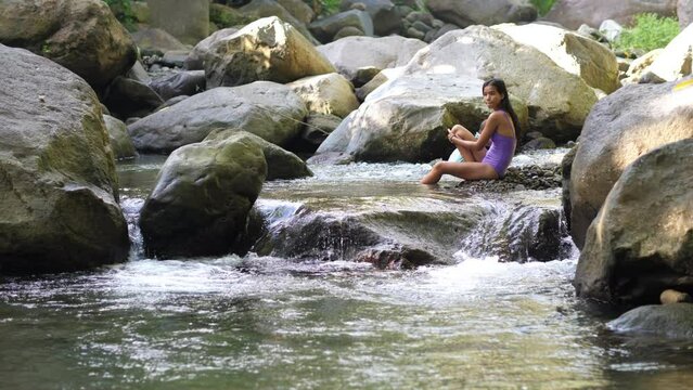 Young woman with little child bathe on rapids in rocky river
