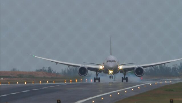 Wide body airliner landing and touching on the runway at Phuket airport. View through the fence. Airplane on the airfield. Travel concept