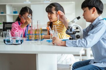 Group of school children using microscopes to study science at school