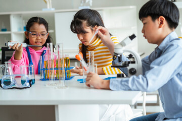 Group of school children using microscopes to study science at school