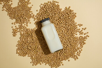 An unlabeled bottle filled with milk displayed on a pile of soybeans. Top view. Concept of natural...