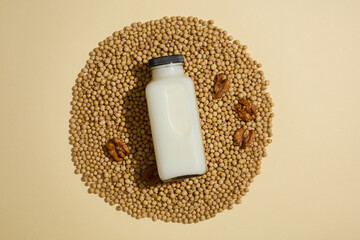 Unbranded milk bottle placed on a pile of soybeans with few walnuts. Soybean (Glycine max) is rich...