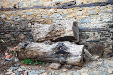 Tree logs waiting on the edge of the wall of the stone house
