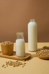 Glass bottles filled with milk are decorated with soybeans contained inside wooden dish and bowl. Soy extract contains antioxidants that can help to protect the skin from damage