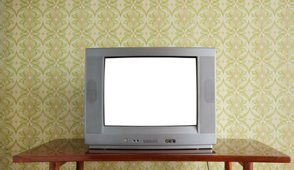 An old TV with a white screen on the bedside table against the background of wallpaper.