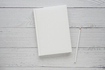 Hard cover notebook, mockup for planner, journal, workbook, album design presentation, minimal composition with white pen on wooden background.