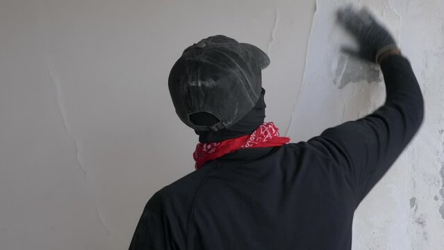 Graffiti artist spraying a colorful portrait mural on a wall