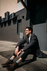 The image depicts a man sitting on the ground outdoors. 4750