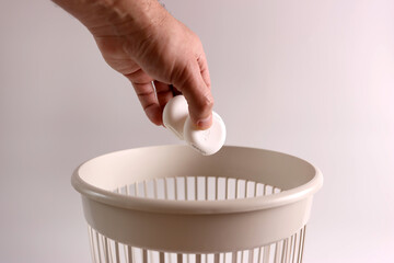 The packaging from the dental floss is thrown into the trash for disposal