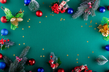 Green Christmas background with Christmas baubles, branches, mistletoe and little trees - 703703857