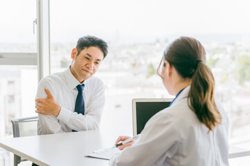 腕の痛みを医師に相談する中年男性（打撲・痺れ・打ち身）
