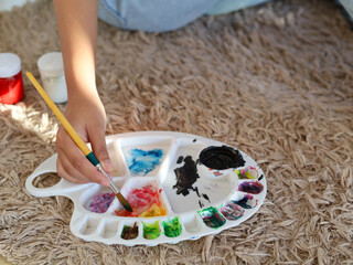 Close up picture of hand with palette and brush painting.