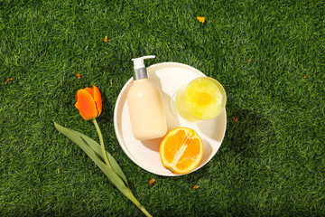 Top view of a round white dish container a pump cosmetic bottle, half an orange and smoothie cup...