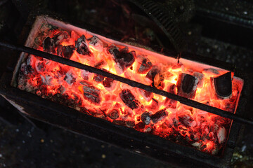 Barbecue grill pit with glowing red and flaming hot charcoal briquettes, Close-Up.