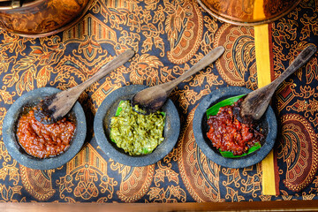 Top view of many type of Indonesian Chili or Sambal Ulek served on top of the table with batik pattern as background. Food served in restaurant, hotel, travel and culinary Indonesia Asian concept.