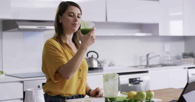 Woman, blender and drinking juice in kitchen for diet, detox and healthy food with green breakfast drink or smoothie. Nutritionist or person with protein shake, fruits and vegetable for wellness