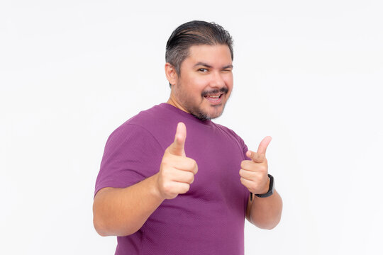An overweight middle aged man winking while making the finger gun gesture. Being cringe and out of touch. Isolated on a white backdrop.