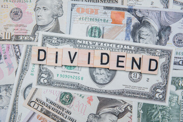 The inscription dividend on the background of American dollars. Investing in Dividend Aristocrats