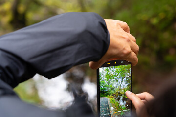 Close up of a woman hands placing the mobile phone vertically to take a photo of a landscape with a...