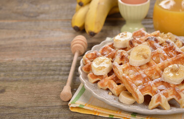 Waffles with banana on a wooden background