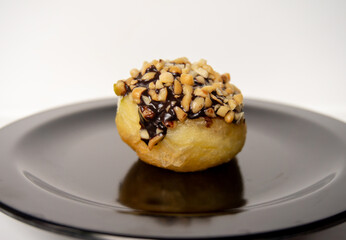 a sweet chocolate peanut-flavored mini donut on a black plate with a white background