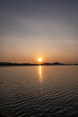 Naklejka premium Sunrise view with colorful sky and the sea, with silhouette of the forest on the background