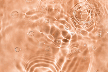 Peachy textured water background with bubbles. Closeup, selective focus, defocus. Color of the year 2024