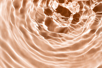 Peachy textured background of waves with ripples on the water. Pool, river, ocean. Close-up, selective focus, defocus. Color of the year 2024