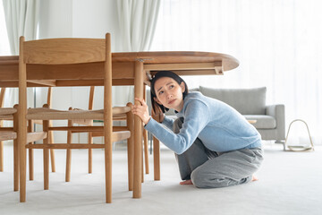 地震で机の下に潜る女性