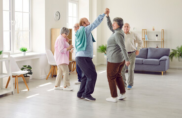 Group of elderly people having a party, dancing and having fun together. Several mature men and women dancing in the living room at home or in a senior care center. Old age, fun, leisure concept