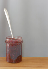 Jar with raspberry jam on a gray background