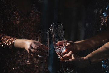 The girls pour champagne into round glasses. Women in a sparkling dress. Full cocktail creamers - le coupe