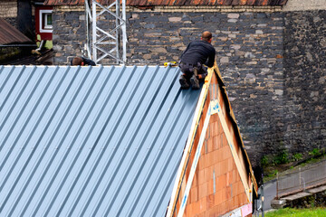 Roofers fastening corrugated sheets on a house roof