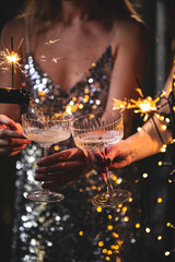 The girls pour champagne into round glasses. Women in a sparkling dress. Christmas garland