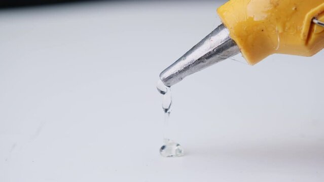 Close-up of hot glue coming out of a glue gun. Hot glue is squeezed out of the gun.