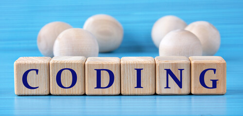 CODING - word on wooden cubes on a blue background with wooden round balls
