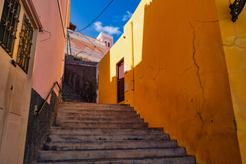A vibrant stairway scene, with warm yellow walls that frame the ascent, capturing the charming character of Ribeira Grande's street architecture under a bright blue sky.
