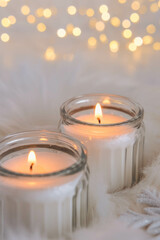 Burning candles on a white fur background with bokeh lights