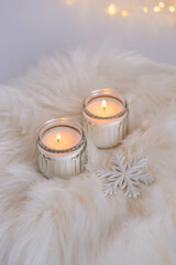 Burning candles on a white fur background with bokeh lights