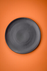 Empty round ceramic plate on a plain background, flatley with copy space
