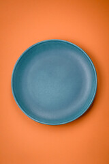 Empty round ceramic plate on a plain background, flatley with copy space