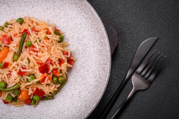 Delicious boiled rice with vegetables peppers, green peas, salt, spices and herbs