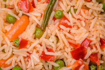 Delicious boiled rice with vegetables peppers, green peas, salt, spices and herbs
