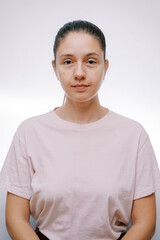 Young serious woman in a beige T-shirt on a gray background. Portrait