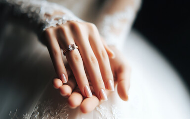 Close-up of the bride's hands and fingers at the wedding hand and engagement ring Woman wearing a white wedding dress - obrazy, fototapety, plakaty