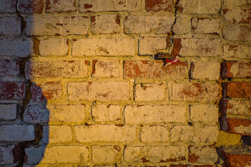 background of an old brick wall, partially destroyed, illuminated by harsh sunlight