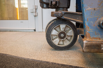 front part with the wheel of a hydraulic storage trolley on the background of the floor and the door of the room
