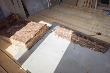 cutting insulation for laying in a frame house under construction.