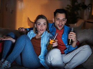 couple movie man watching woman entertainment tv home horror scared scary fear shock young  female leisure night together home sofa television film emotion thriller beer drink alcohol bottle - obrazy, fototapety, plakaty