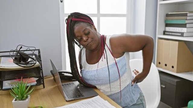 Unhappy african american business woman worker feeling the burn of backache while sitting at office table